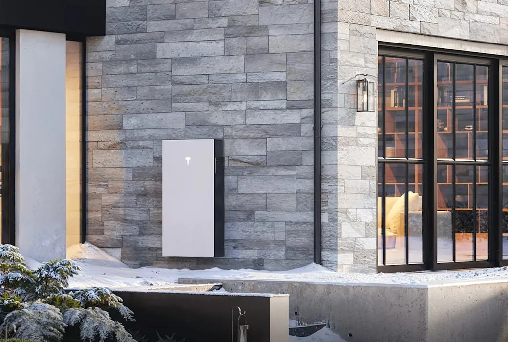 Tesla Powerwall installed flush on the stone exterior wall of a modern home